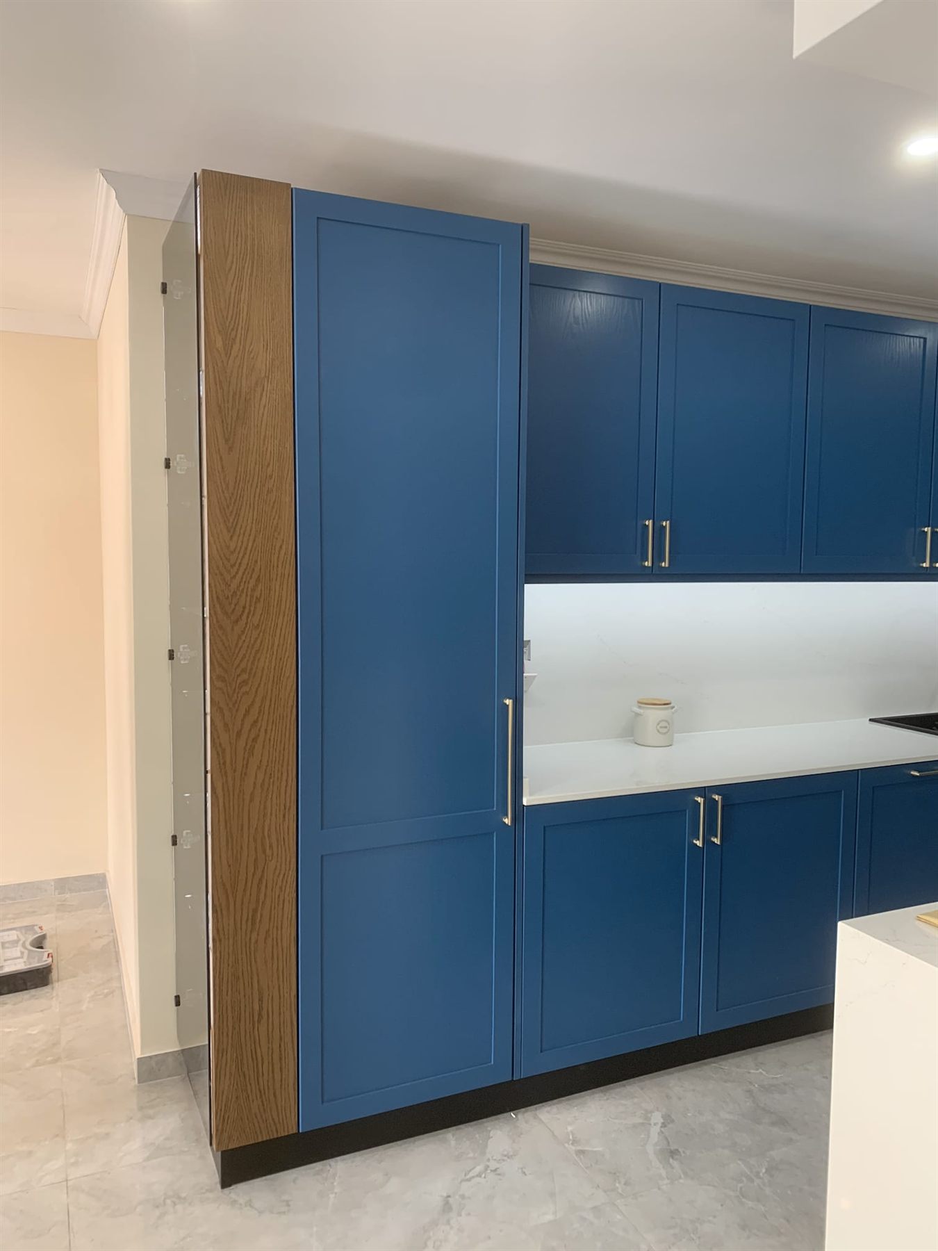 Deep blue shaker kitchen with oak trim and brass handles