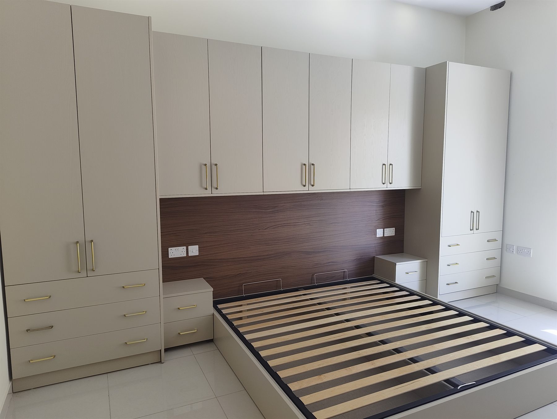 Fitted overbed wardrobes with walnut panel
