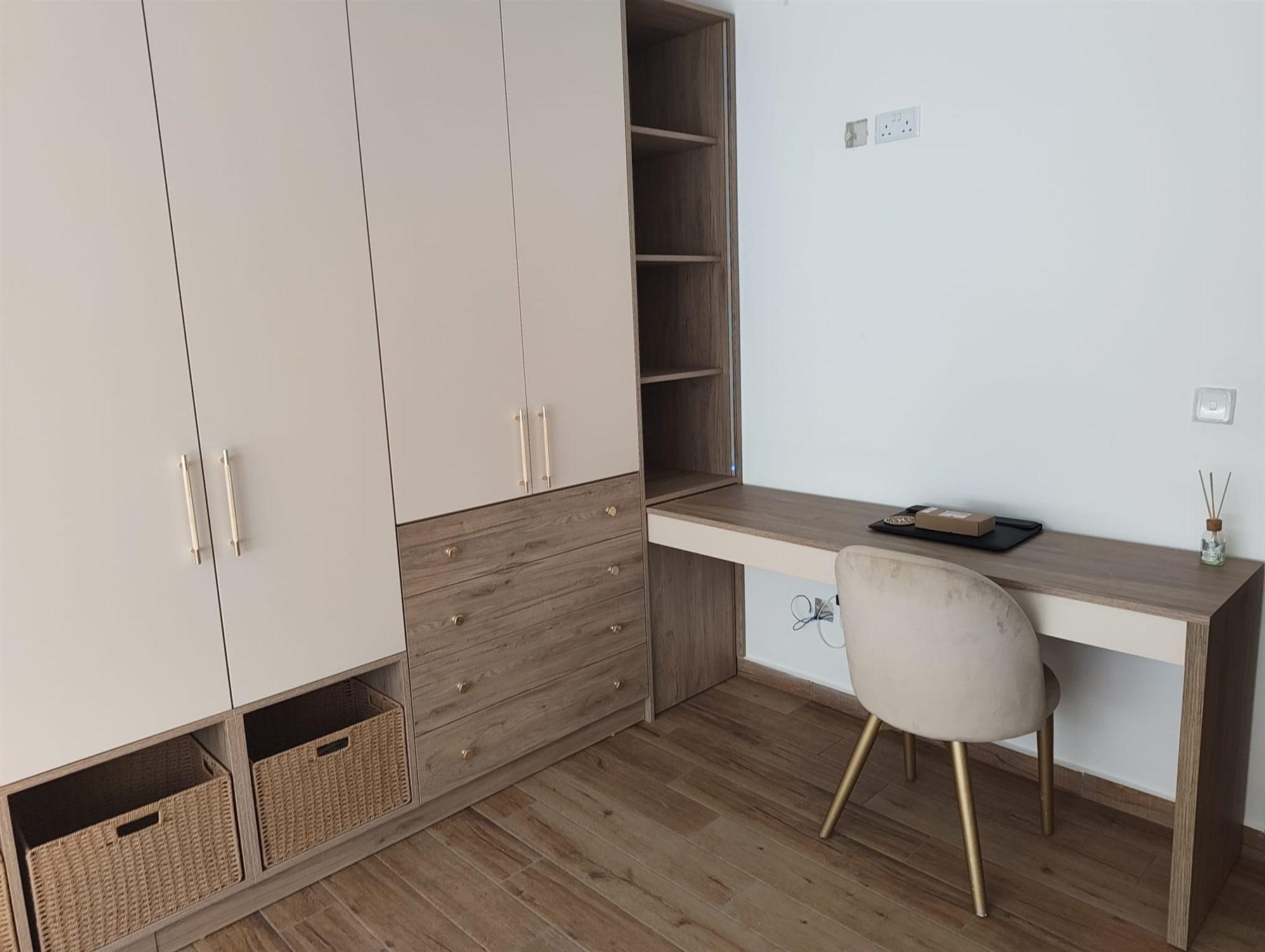 Fitted wardrobes with integrated desk and woven storage baskets